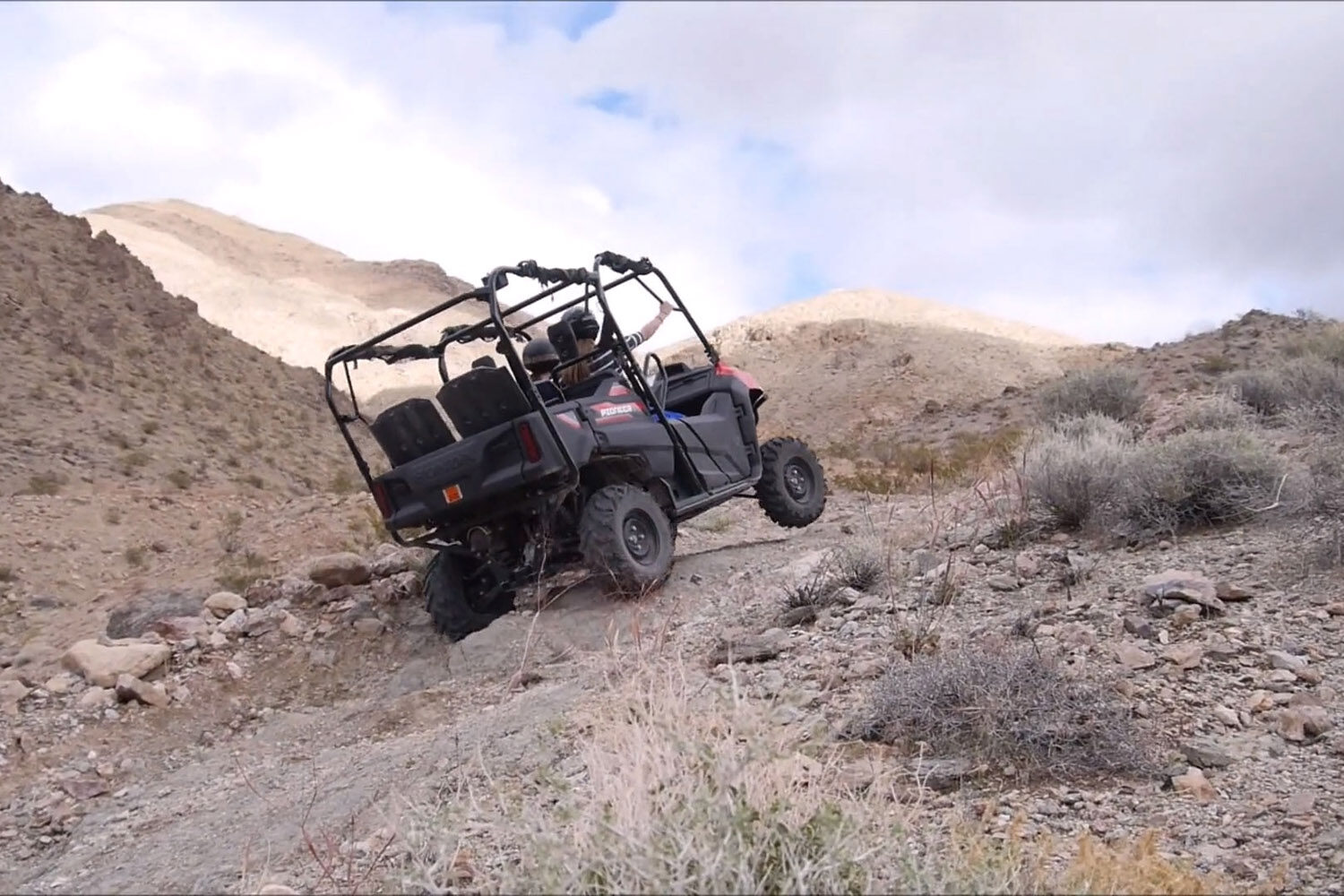 An ATV riding precariously on a steep mountain track