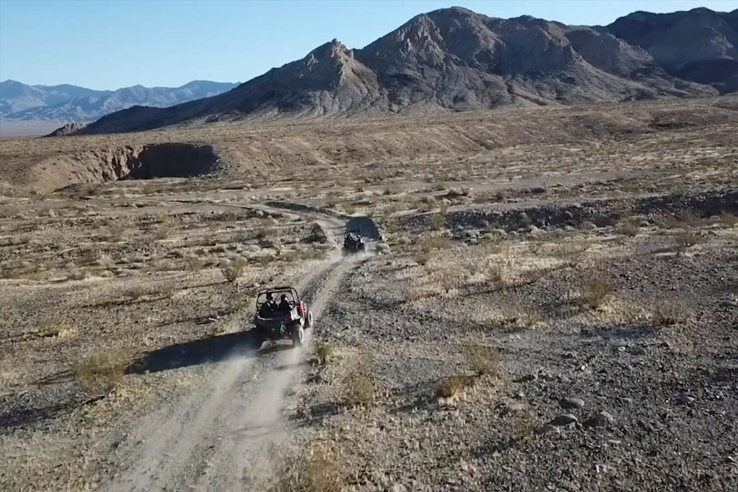 One ATV guiding another through a vast desert wilderness