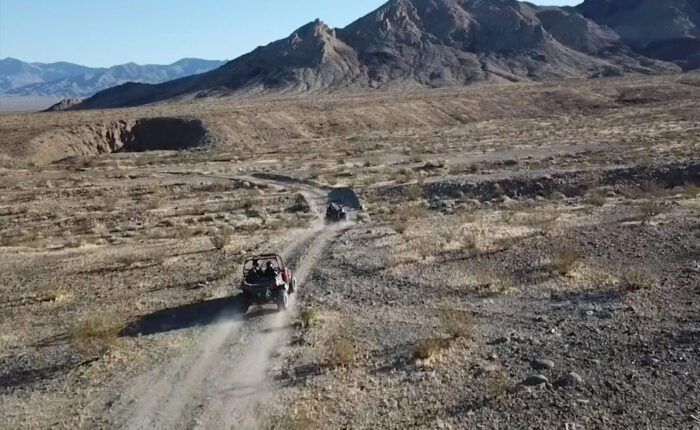 One ATV guiding another through a vast desert wilderness