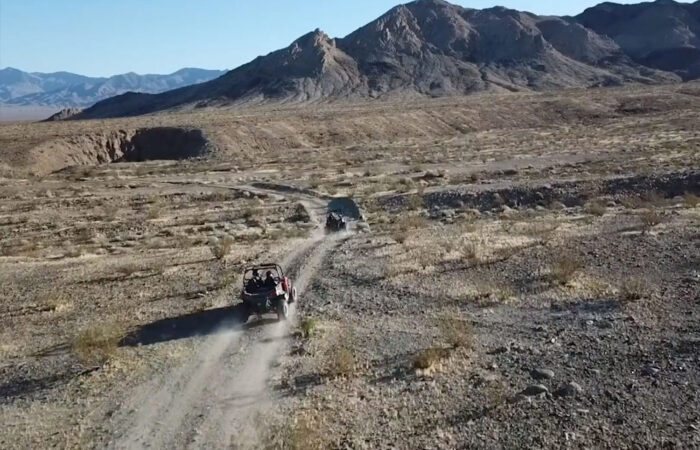 One ATV guiding another through a vast desert wilderness