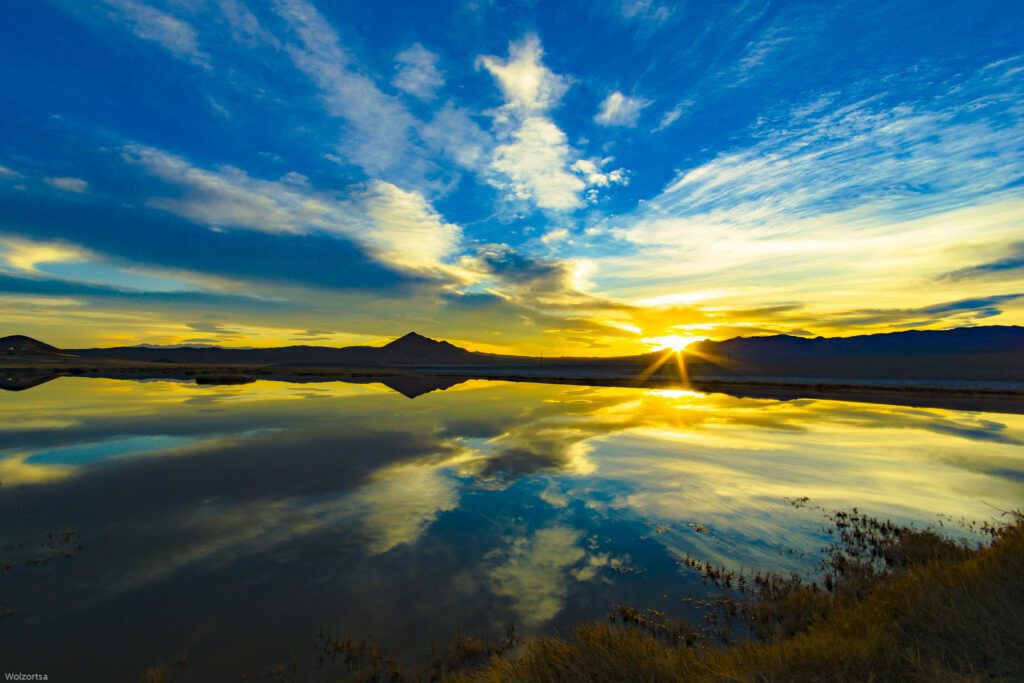 Sunset over a calm lake reflecting vibrant clouds and sky.