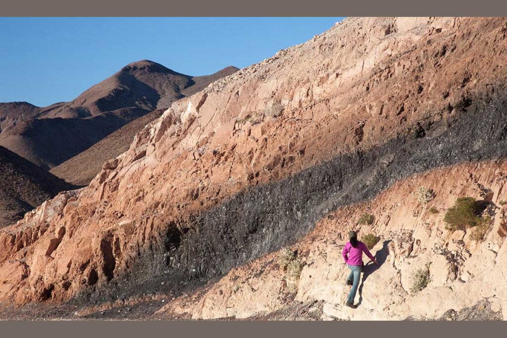 Women studying the rocks on the side of a mountain