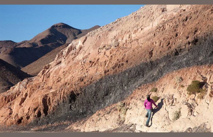 Women studying the rocks on the side of a mountain