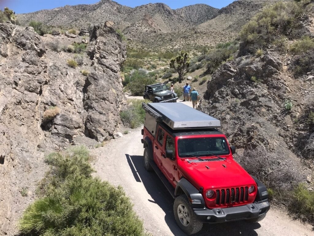 Three people and two Jeeps in a desert mountain pass